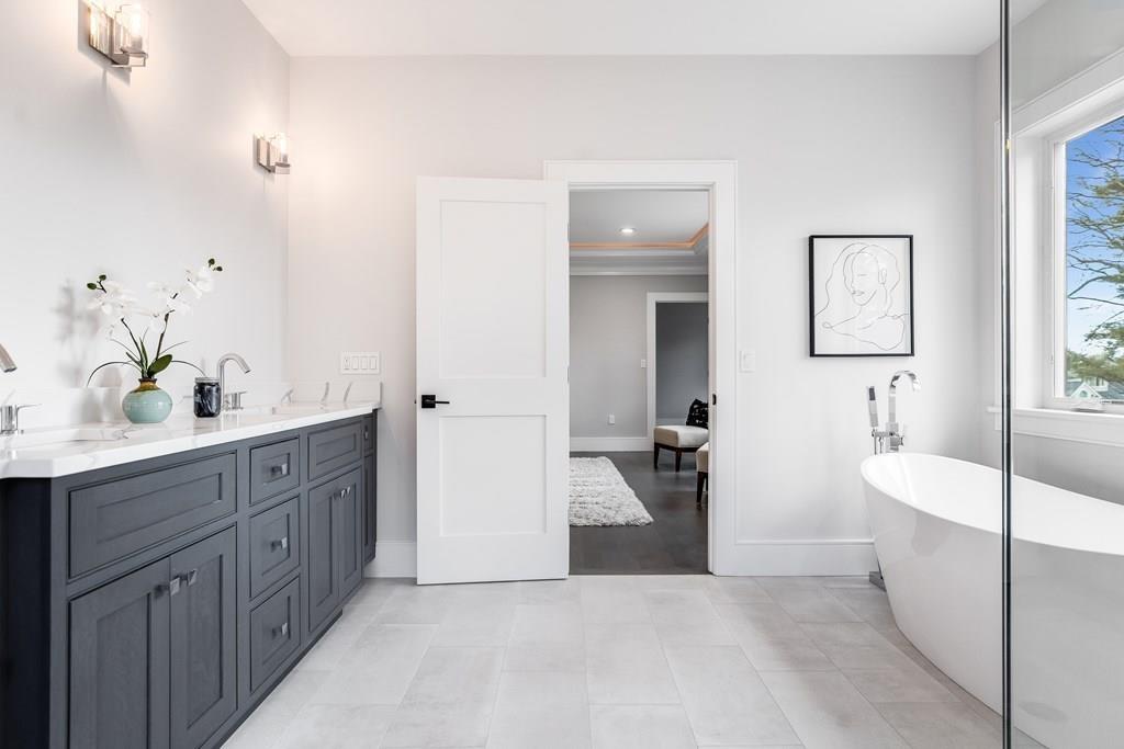 819 Dedham Street Newton, MA 02459 - Photo 25 of 40 a spacious bathroom with a double vanity sink a large mirror and a bathtub