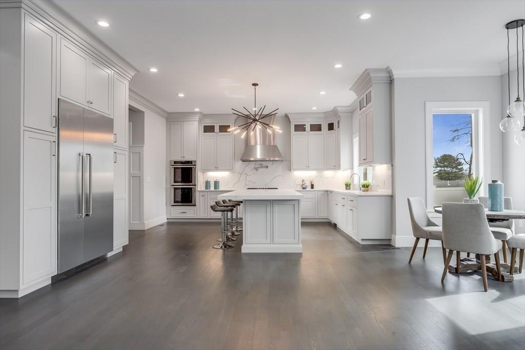 819 Dedham Street Newton, MA 02459 - Photo 4 of 40 a large kitchen with stainless steel appliances kitchen island a large counter top a sink and a refrigerator