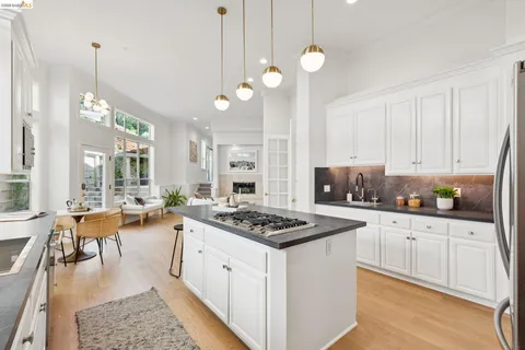 a kitchen with granite countertop a stove a sink a center island a dining table and chairs