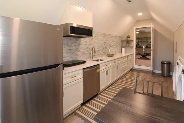 a large white kitchen with stainless steel appliances a refrigerator and a stove