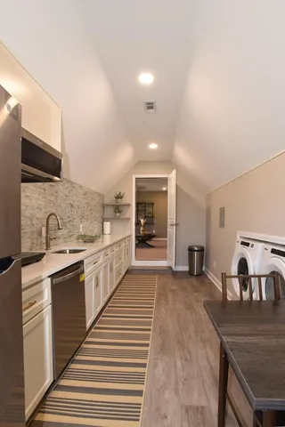 a large kitchen with stainless steel appliances granite countertop a sink and dishwasher a stove top oven with wooden floor