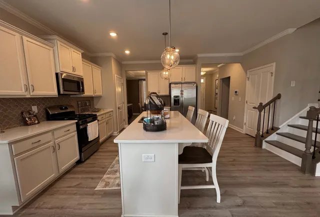 a kitchen with stainless steel appliances kitchen island granite countertop a stove a sink a microwave a kitchen island with a dining table and chairs
