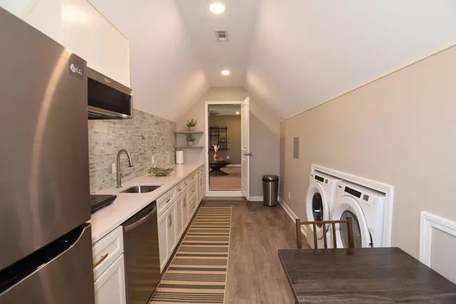 a large white kitchen with granite countertop a stove a sink and a refrigerator