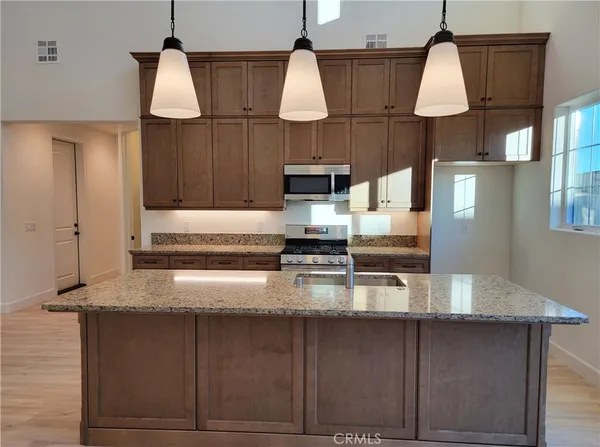 a kitchen with stainless steel appliances granite countertop a sink a stove a refrigerator a center island with wooden floor