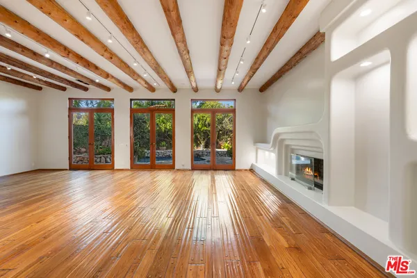 a view of an empty room with wooden floor fireplace and a window