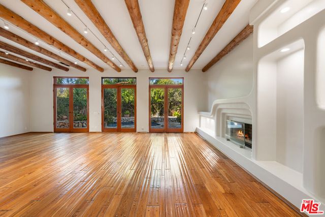 a view of an empty room with wooden floor fireplace and a window
