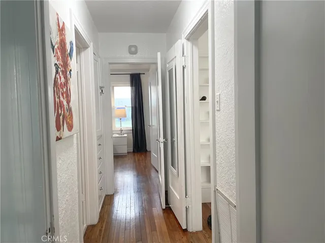 a view of a hallway with wooden floor and a bathroom