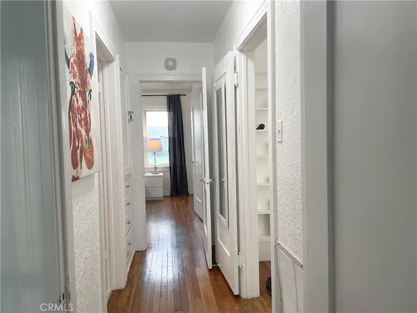 a view of a hallway with wooden floor and a bathroom