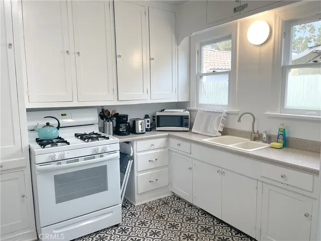 a kitchen with cabinets appliances a sink and a window