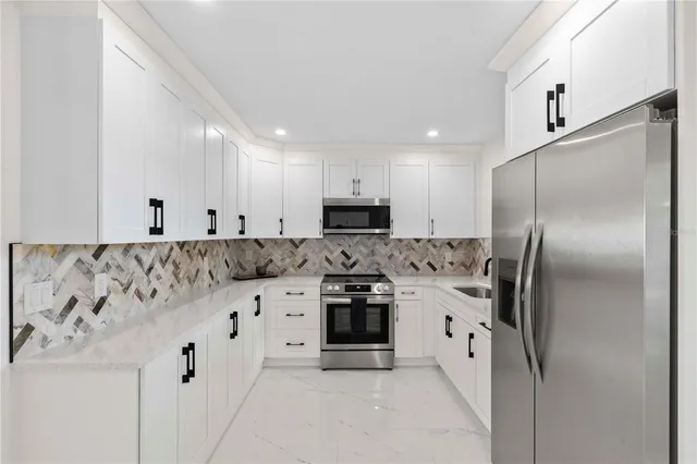 a kitchen with granite countertop white cabinets and stainless steel appliances