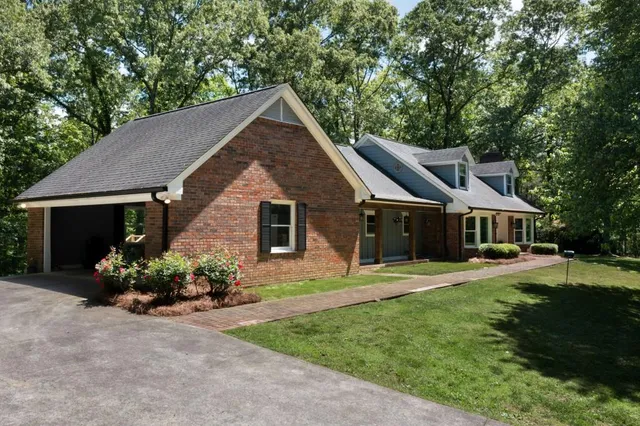 a view of a brick house with potted plants and a large tree