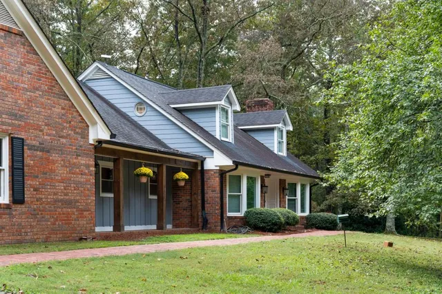 a front view of a house with a garden and trees