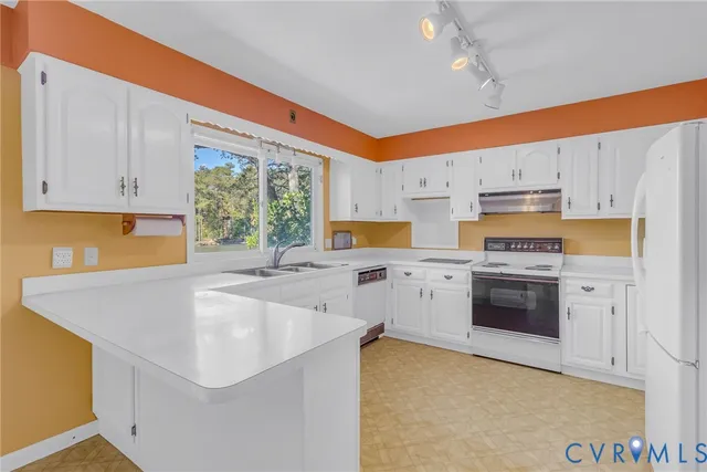 a large white kitchen with granite countertop a sink and dishwasher a stove with wooden floor