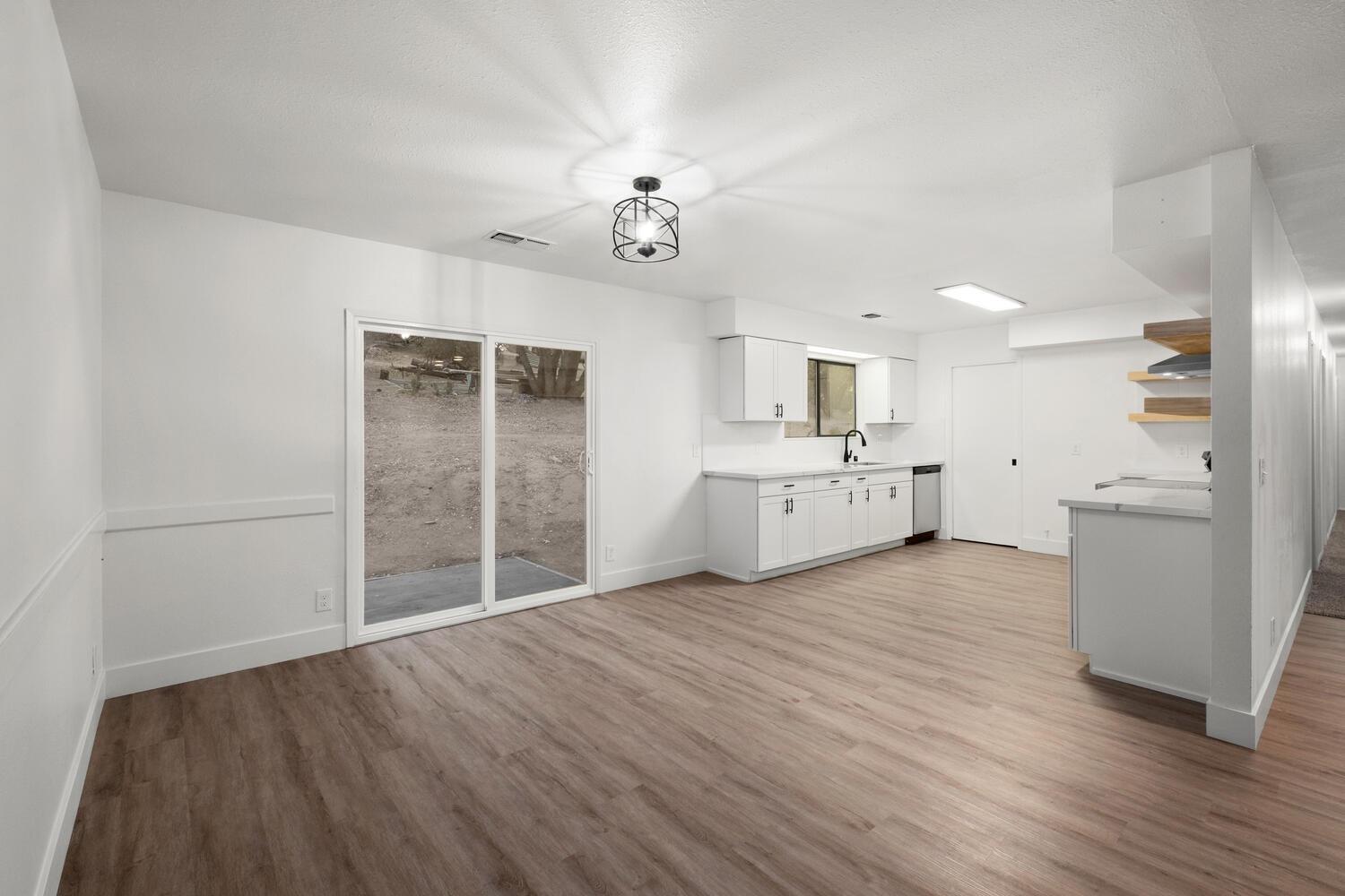 51202 Rusty Lane Oakhurst, CA 93644 - Photo 10 of 27 an empty room with wooden floor and a kitchen