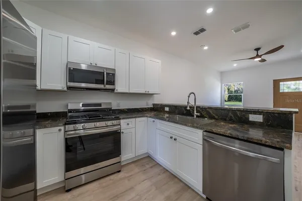 a kitchen with stainless steel appliances granite countertop a sink a stove a microwave and cabinets