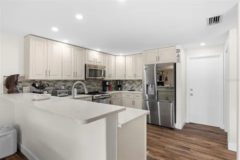 a kitchen with a refrigerator a stove top oven a sink and dishwasher with wooden floor