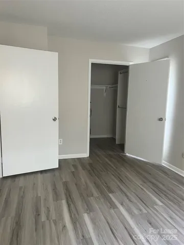 a view of an empty room with wooden floor and closet