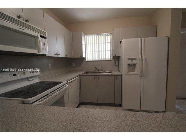 6761 Northwest 182nd Street, Unit 104 Hialeah, FL 33015 - Photo 3 of 12 a kitchen with a refrigerator stove and microwave