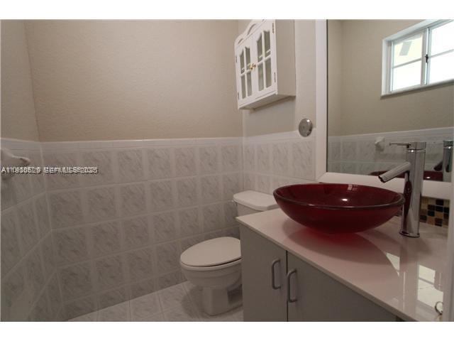 6761 Northwest 182nd Street, Unit 104 Hialeah, FL 33015 - Photo 4 of 12 a bathroom with a sink a toilet and a mirror