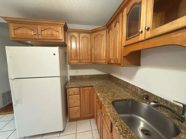 a view of a refrigerator in kitchen and a window in an empty room