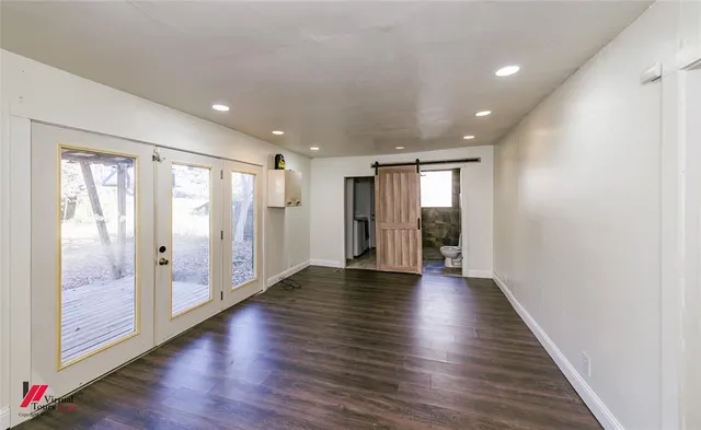 a view of an empty room with wooden floor and windows