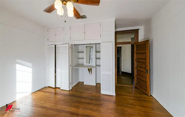 a view of empty room with wooden floor and ceiling fan