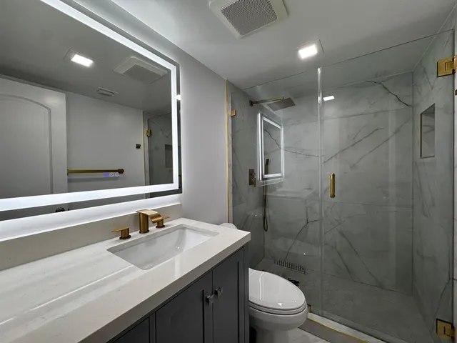 a bathroom with a sink a toilet and shower