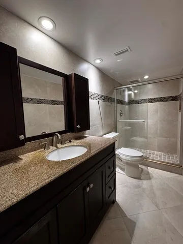 a bathroom with a granite countertop sink a toilet and mirror