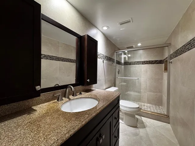 a bathroom with a granite countertop sink toilet and shower