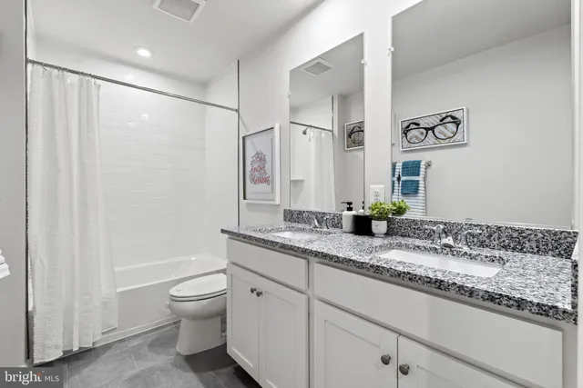 a bathroom with a granite countertop sink a toilet and a shower