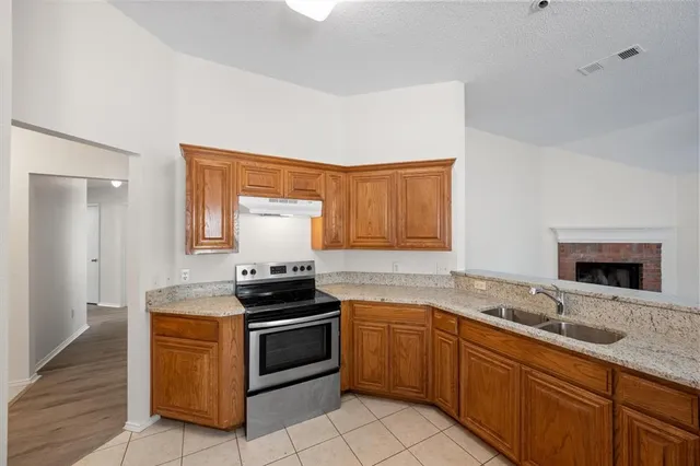 a kitchen with granite countertop a stove sink and cabinets