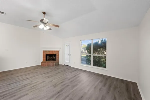 a view of an empty room with a window and wooden floor