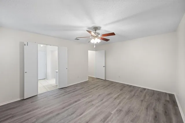 an empty room with wooden floor and ceiling fan