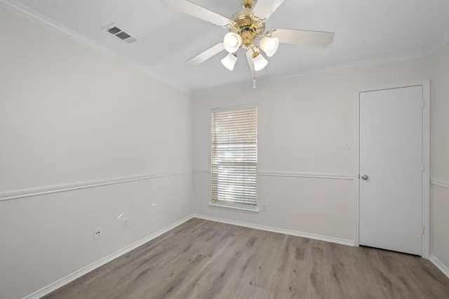 an empty room with wooden floor chandelier fan and windows