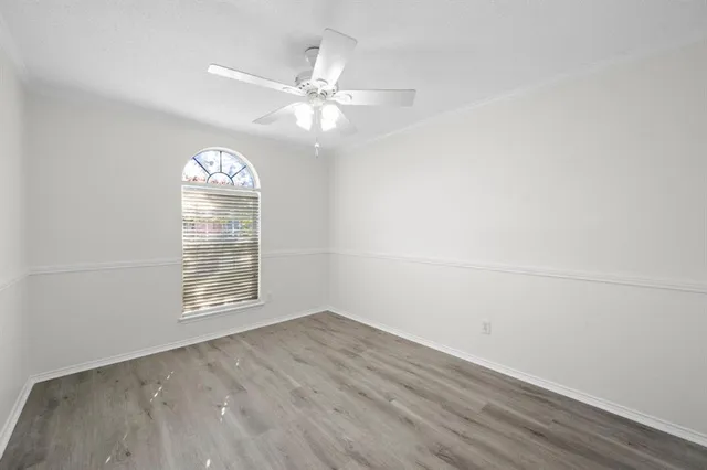 an empty room with wooden floor fan and windows