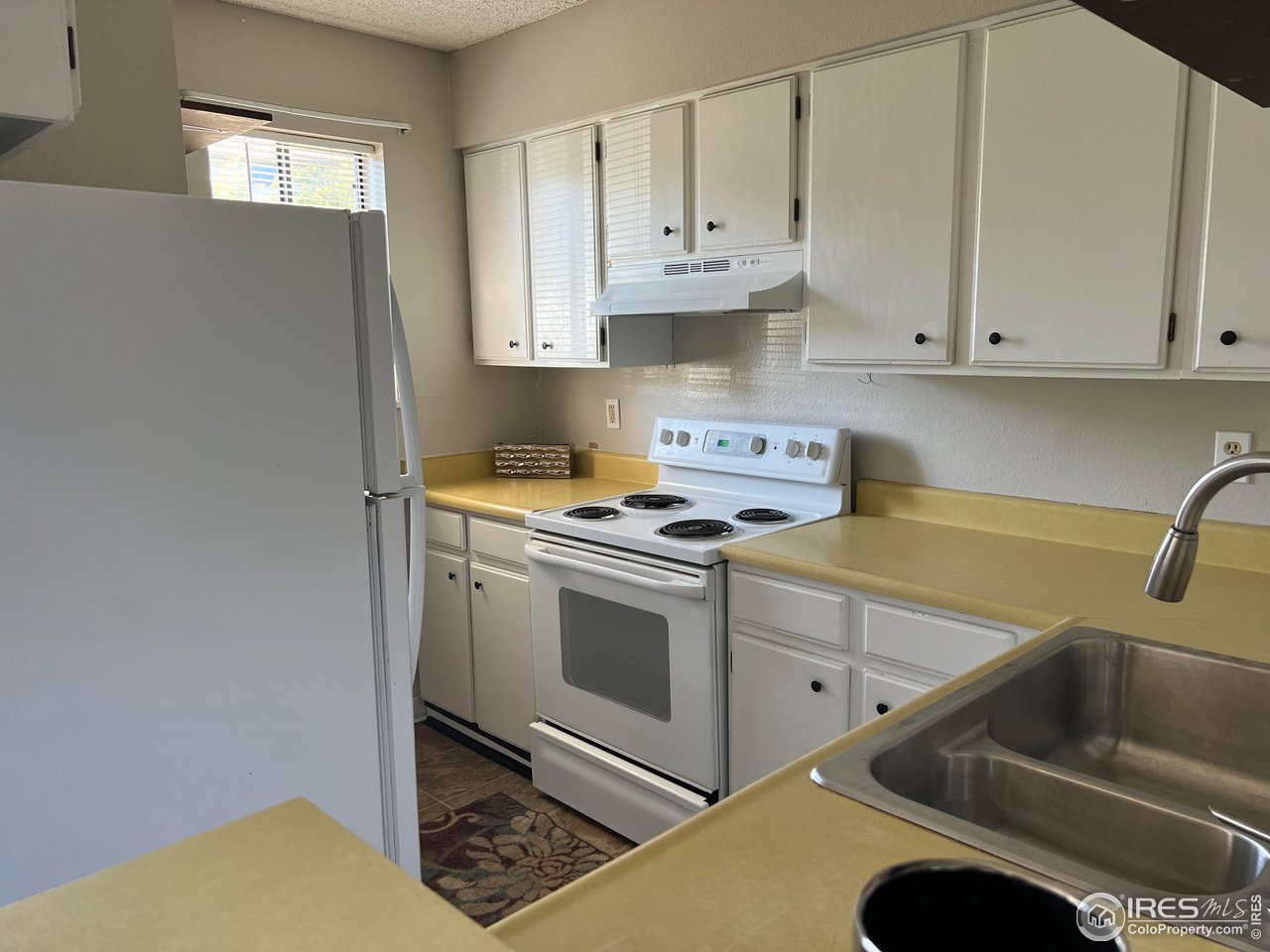 1705 Heatheridge Road, Unit 104 Fort Collins, CO 80526 - Photo 5 of 14 a kitchen with granite countertop white cabinets and white appliances