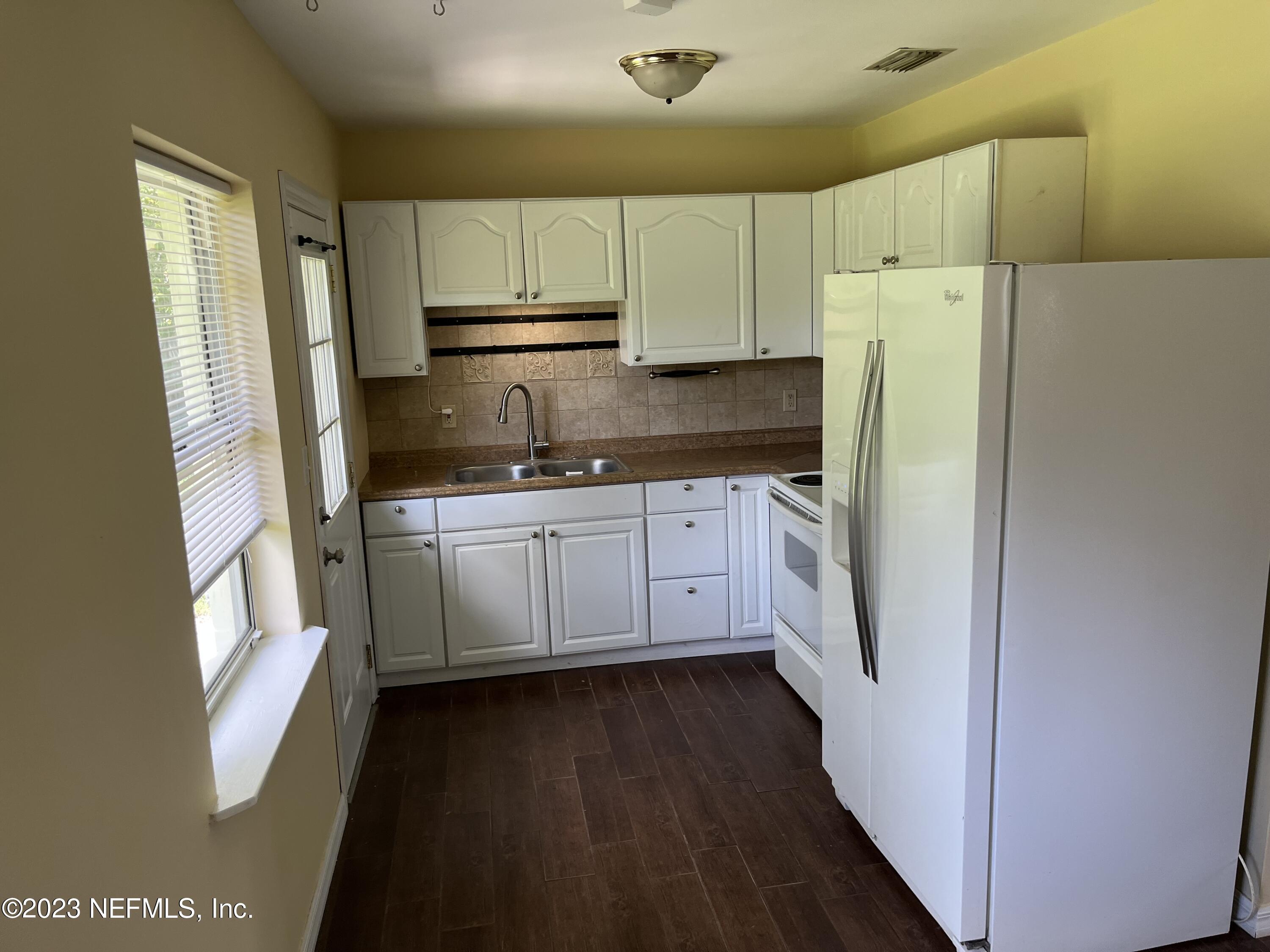 5418 Juno Drive Jacksonville, FL 32207 - Photo 6 of 19 a kitchen with a sink a refrigerator a window and cabinets