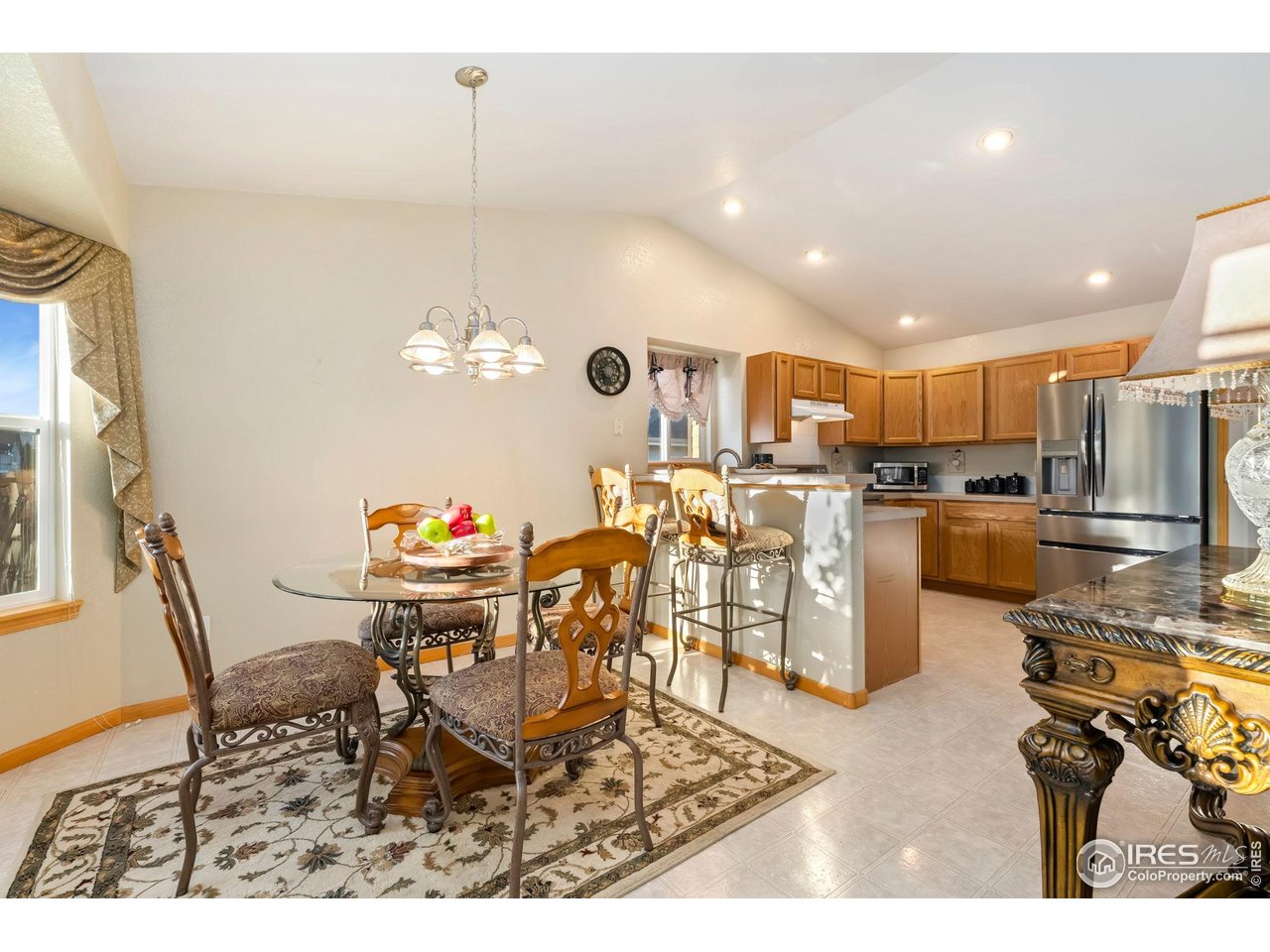 623 Foxtail Way Severance, CO 80550 - Photo 15 of 27 a kitchen with stainless steel appliances kitchen island granite countertop a refrigerator a stove a sink dishwasher with a dining table and chairs
