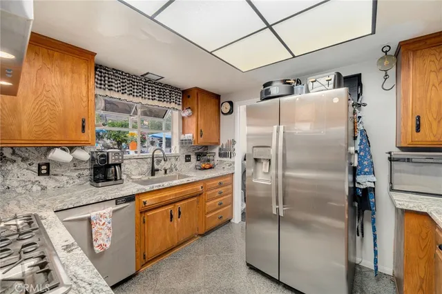 a kitchen with stainless steel appliances granite countertop a refrigerator a sink and white cabinets