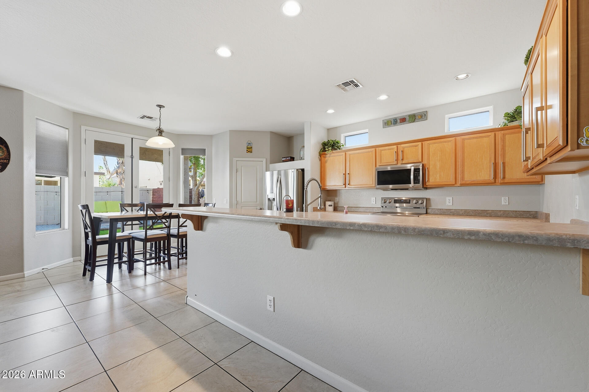 3273 East Fairview Street Gilbert, AZ 85295 - Photo 13 of 37 a kitchen with stainless steel appliances granite countertop a stove top oven a sink a dining table and chairs with wooden floor