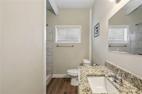 a bathroom with a granite countertop toilet a sink and a window