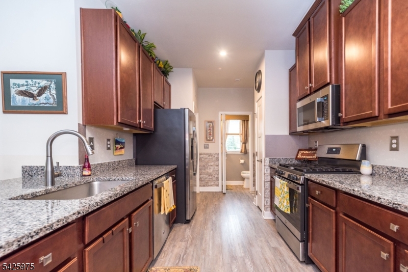 2 Sharp Shinned Court Washington, NJ 07882 - Photo 8 of 27 a kitchen with stainless steel appliances granite countertop a stove a sink dishwasher a refrigerator and wooden cabinets with wooden floor