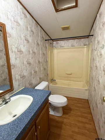 a bathroom with a granite countertop sink toilet mirror vanity and shower