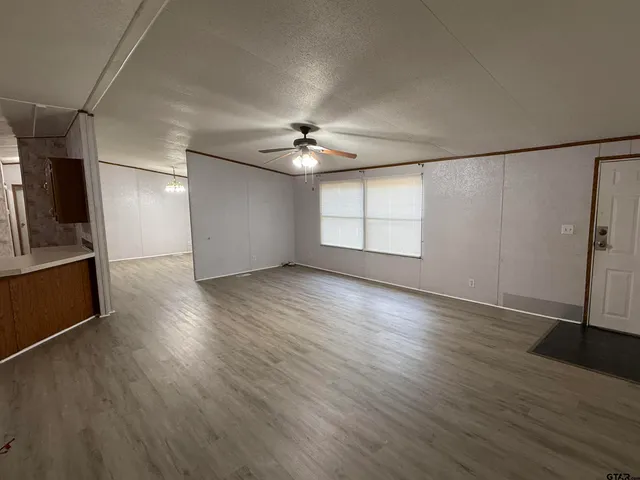 an empty room with wooden floor fan and windows