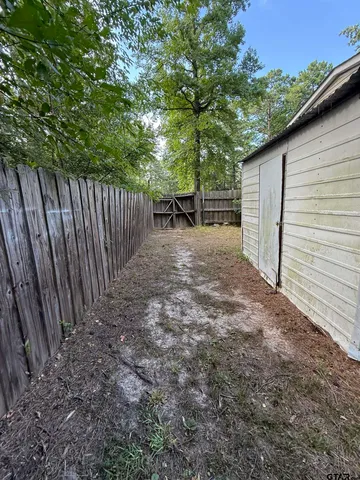a view of backyard of house with wooden fence