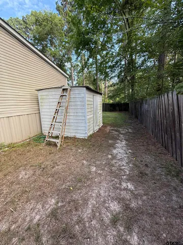 a view of a backyard with wooden fence and a large tree