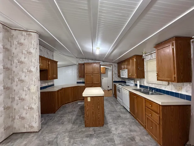 a large kitchen with stainless steel appliances granite countertop a stove a sink dishwasher and a refrigerator