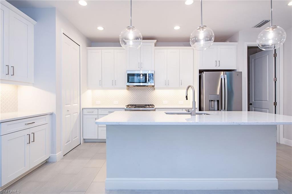 2409 Ariane Drive Naples, FL 34112 - Photo 7 of 16 a kitchen with kitchen island a sink stainless steel appliances and cabinets