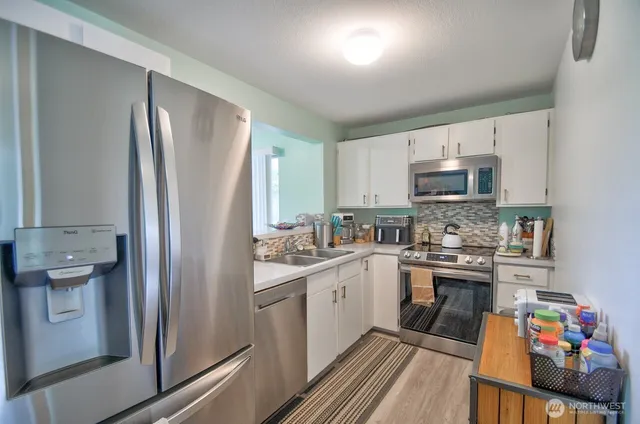 a kitchen with a sink a refrigerator a microwave a stove and cabinets