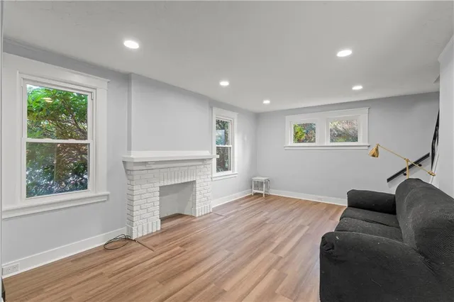 a view of a livingroom with a fireplace wooden floor and windows